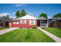 Charming red single-story home with a well-manicured front yard and white trim accents on a sunny day at 1955 Ingalls St, Lakewood, CO 80214