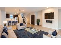 Open-concept living room with modern fireplace, recessed lighting, and adjacent kitchen and staircase at 3150 Vallejo St, Denver, CO 80211