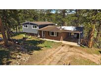 Charming multi-story home with a brick facade and attached carport nestled amongst tall pine trees at 29827 Gigi Rd, Evergreen, CO 80439
