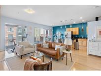 Bright living room featuring hardwood floors, a modern leather sofa, and balcony access at 1438 Little Raven St # 310, Denver, CO 80202