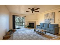Inviting living room features a fireplace, comfortable seating, and sliding glass doors to a charming balcony at 10293 E Peakview Ave # F104, Englewood, CO 80111