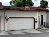 Exterior view of home featuring a two-car garage, red-tiled roof, and American flag at 1511 Belero St, Broomfield, CO 80020