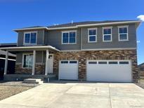 Beautiful two-story home with brick and siding, white garage doors, and covered front porch, and a concrete driveway at 1866 Sawtooth Mountain Dr, Berthoud, CO 80513