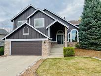 Charming two-story home featuring a well-manicured lawn, complemented by a stone facade and a spacious attached garage at 9714 Chanteclair Cir, Highlands Ranch, CO 80126