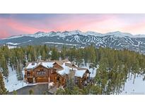 Stunning log home with snow-covered roof, nestled among trees and mountains, offering picturesque views at 378 Juniata Cir, Breckenridge, CO 80424