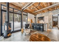Open concept living space with wood ceiling, stone accent wall, and fireplace, creating a cozy atmosphere at 2383 Tiger Rd, Breckenridge, CO 80424