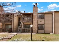Exterior view of the home featuring a stone chimney, balcony, and well-maintained lawn at 1842 S Pitkin Cir # A, Aurora, CO 80017