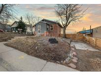 Charming exterior showcasing a two-story house with a unique stone front, landscaped yard, and tree at 1047 Meade St, Denver, CO 80204