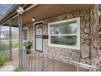 Close-up of stone-clad front porch with security door, large window, and metal railing at 1293 S Perry St, Denver, CO 80219