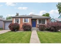 Charming brick home with lush landscaping, gray garage, and a bright blue front door at 3285 S Delaware St, Englewood, CO 80110