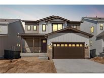 Charming two-story home with a two-car garage, stone accents, and a covered front porch at 8893 Springsong Ln, Littleton, CO 80125