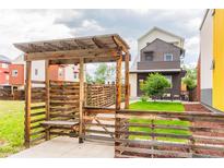 Charming front yard with lush green lawn and wooden pergola walkway at 6892 Juniper Ct, Arvada, CO 80007