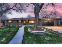 Charming brick home featuring manicured front yard, blue garage door, and walkway leading to an inviting entrance at 2674 S Krameria St, Denver, CO 80222