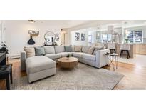 Bright living room featuring a large sectional, modern round coffee table, and an open concept to the kitchen at 2674 S Krameria St, Denver, CO 80222