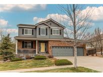 Charming two-story home with a well-manicured lawn, a yellow front door, and a three-car garage at 6488 S Kewaunee Way, Aurora, CO 80016