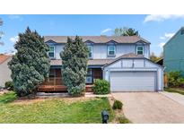 Two-story home with light blue paint, a two-car garage, lawn, and a charming front porch at 15909 E Ford Pl, Aurora, CO 80017
