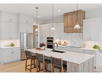 A modern, open kitchen with a large island, stainless steel appliances, and stylish pendant lighting at 1425 Burt Ave, Berthoud, CO 80513