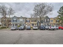 View of colorful townhomes with ample parking, nestled near mature trees and a cloudy sky at 1240 S Idalia St, Aurora, CO 80017