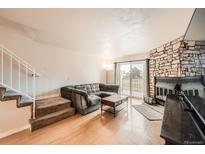 Inviting living room with stone fireplace, wood floors, and a comfortable sectional sofa at 1240 S Idalia St, Aurora, CO 80017