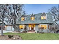 Charming two-story home with a well-manicured lawn, complemented by mature trees and a welcoming entrance at 14475 Crabapple Rd, Golden, CO 80401