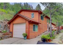 Charming home featuring wood siding, attached garage, and picturesque landscaping at 11220 S Deer Creek Rd, Littleton, CO 80127
