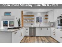 Bright kitchen featuring white cabinets, stainless steel appliances, and wood floating shelves at 32187 Sylvan Rd, Golden, CO 80403