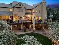 Expansive backyard with multi-level decks, spiral staircase, lush lawn, and mature trees, perfect for outdoor living at 81 Falcon Hills Dr, Highlands Ranch, CO 80126