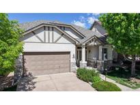 Charming home with a two-car garage, covered porch, and manicured landscaping under a bright blue sky at 6187 Reed Way, Arvada, CO 80003