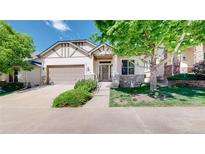 Charming front exterior featuring stone accents, a well-manicured lawn, and an attached two-car garage at 6187 Reed Way, Arvada, CO 80003