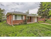 Charming red brick home featuring a well-manicured lawn and an attached one car garage at 1325 Geneva St, Aurora, CO 80010