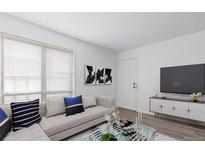 Bright living room features a decorative fireplace, large windows, and modern furnishings at 7185 S Gaylord St # G13, Littleton, CO 80122