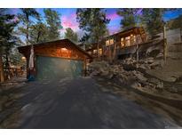 Charming cabin with a two-car garage and a deck, surrounded by a lush, wooded landscape at 27407 Upper Cold Spg Gulch Rd, Golden, CO 80401