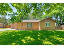 Charming brick home featuring a bright yellow door, attached garage, and lush front lawn at 3925 Newland St, Wheat Ridge, CO 80033