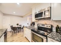Bright kitchen features stainless steel appliances, granite countertops, and a cozy dining area at 381 S Ames St # F208, Lakewood, CO 80226