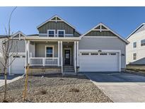 Charming gray two-story home featuring a covered porch, white trim, and a two-car garage at 968 Congress Pl, Elizabeth, CO 80107