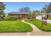 Charming brick home featuring a well-manicured lawn, curved walkway, and mature landscaping at 798 Alkire St, Lakewood, CO 80401
