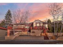 Charming multi-level home with a red-trimmed exterior and a spacious front deck, set against a colorful sky at 4215 W Byron Pl, Denver, CO 80212