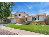 Charming two-story home featuring a lush lawn, brick accents, and an attached two car garage at 7276 W 83Rd Way, Arvada, CO 80003
