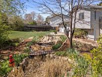 Landscaped backyard featuring a decorative pond with bridge, table set and spacious lawn area at 17900 E Mexico Dr, Aurora, CO 80017