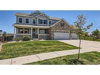 Charming two-story home with a brick and siding exterior, well-manicured lawn, and a three-car garage at 22197 E Stroll Ave, Parker, CO 80138