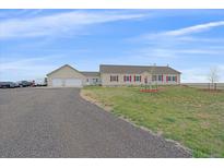 Tan home with attached garage, red shutters, and long gravel driveway at 14551 N Harback Rd, Keenesburg, CO 80643