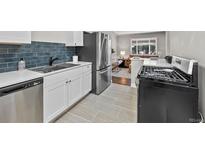 Well-lit kitchen with stainless steel appliances, subway tile backsplash, and view to living room at 500 S Pennsylvania St # 520, Denver, CO 80209