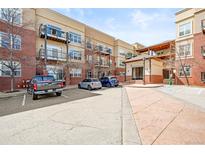 Exterior view of the apartment building, featuring stucco and brick, with ample parking at 5401 S Park Terrace Ave # 105A, Greenwood Village, CO 80111