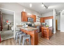 A modern kitchen features stainless steel appliances, wooden cabinets, granite countertops and bar seating at 5401 S Park Terrace Ave # 105A, Greenwood Village, CO 80111