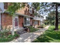 Charming brick townhome with landscaped front yard and inviting entryway, showcasing curb appeal at 7396 S Knolls Way, Centennial, CO 80122
