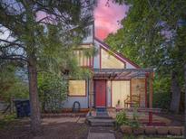 Charming home with a red door, exposed beams, and lush trees at 1076 S Leyden St, Denver, CO 80224