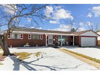 Brick ranch house with a snow-covered yard and attached garage at 6445 Iris St, Arvada, CO 80004