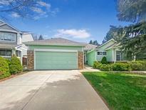 Charming green home featuring an attached garage and a well-maintained lawn at 9806 Hooker Ct, Denver, CO 80031