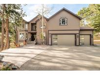Stunning two-story home featuring a wide driveway and a spacious three-car garage, nestled in a serene, wooded environment at 2253 Augusta Dr, Evergreen, CO 80439