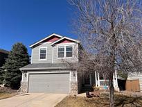 Charming gray two-story home featuring a two-car garage and stone accents at 9889 Aftonwood St, Highlands Ranch, CO 80126